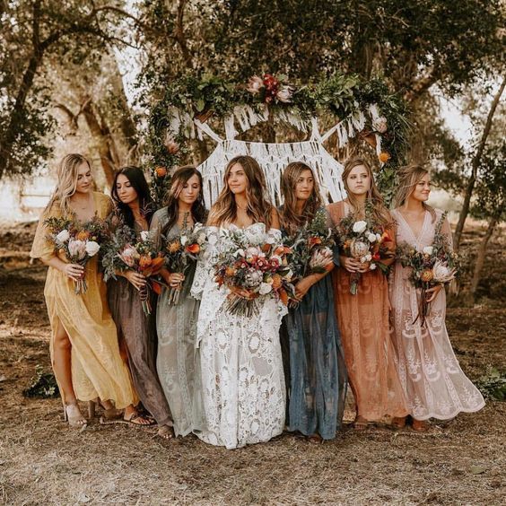 a group of women standing next to each other in front of a wooden structure with flowers on it