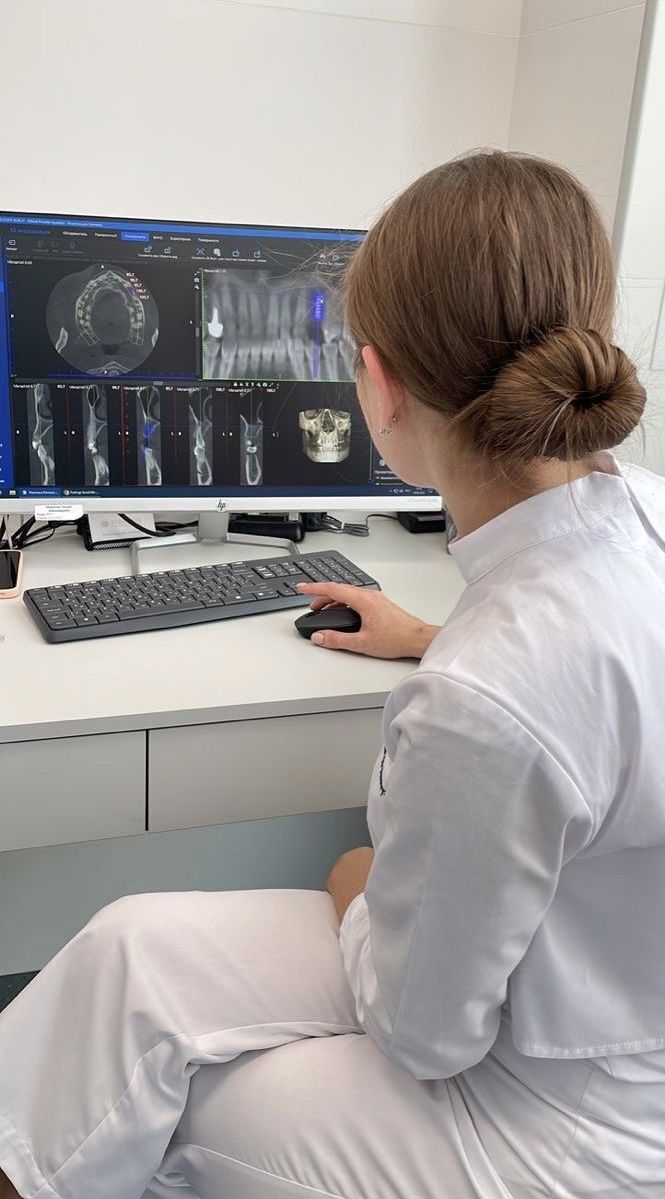 a woman sitting at a desk in front of a computer with an x - ray on it