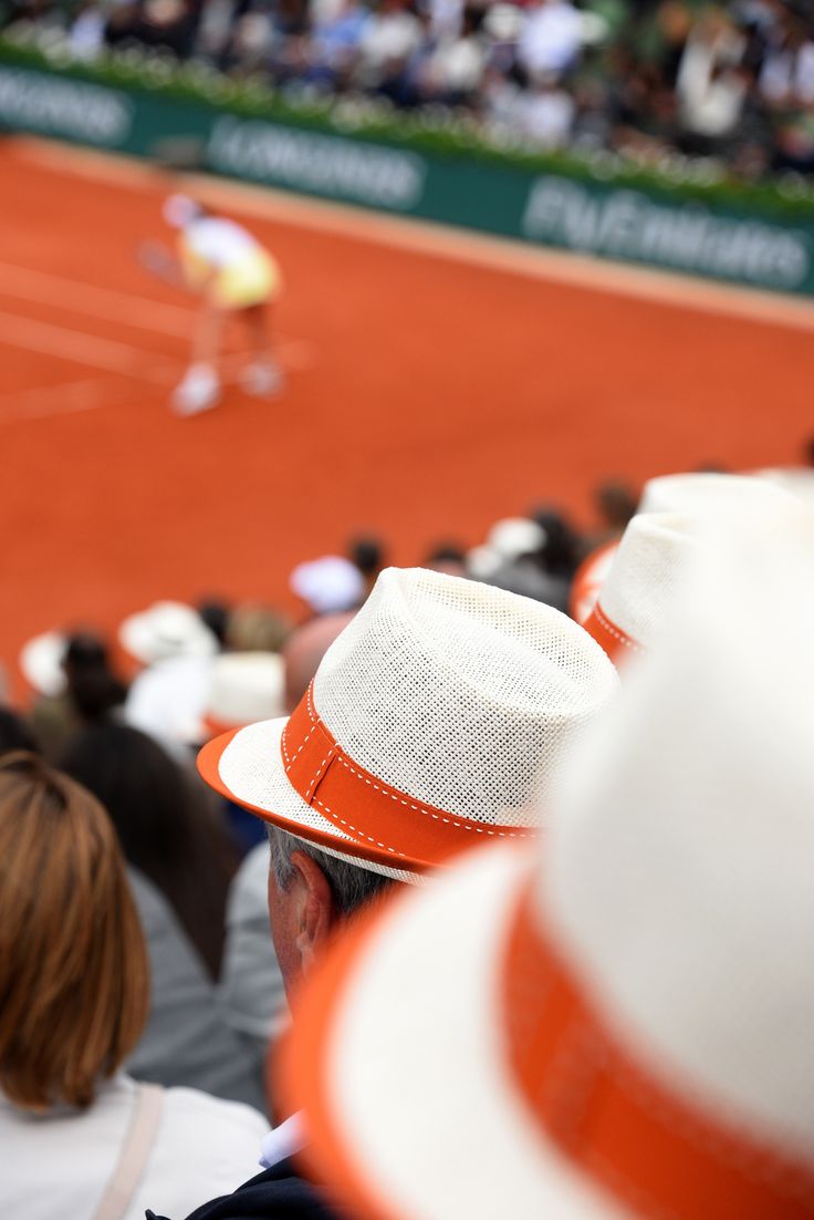 people watching a tennis match on a clay court