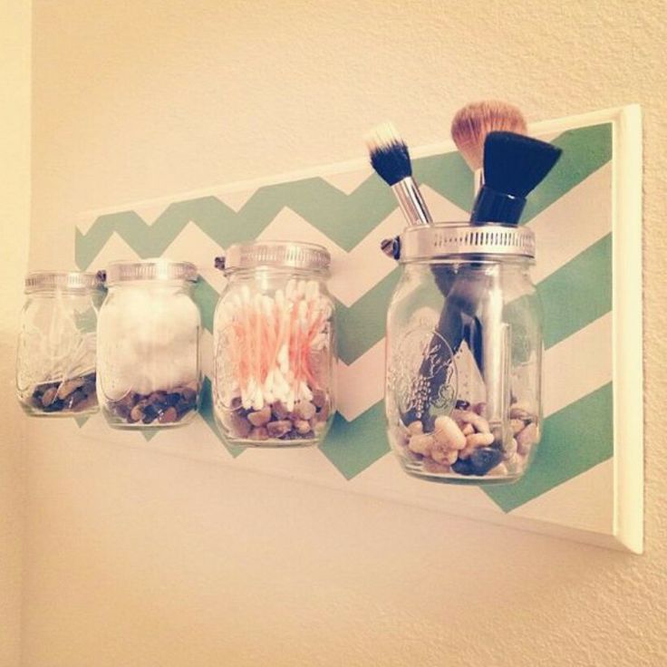 four jars filled with different types of items on top of a shelf next to a wall