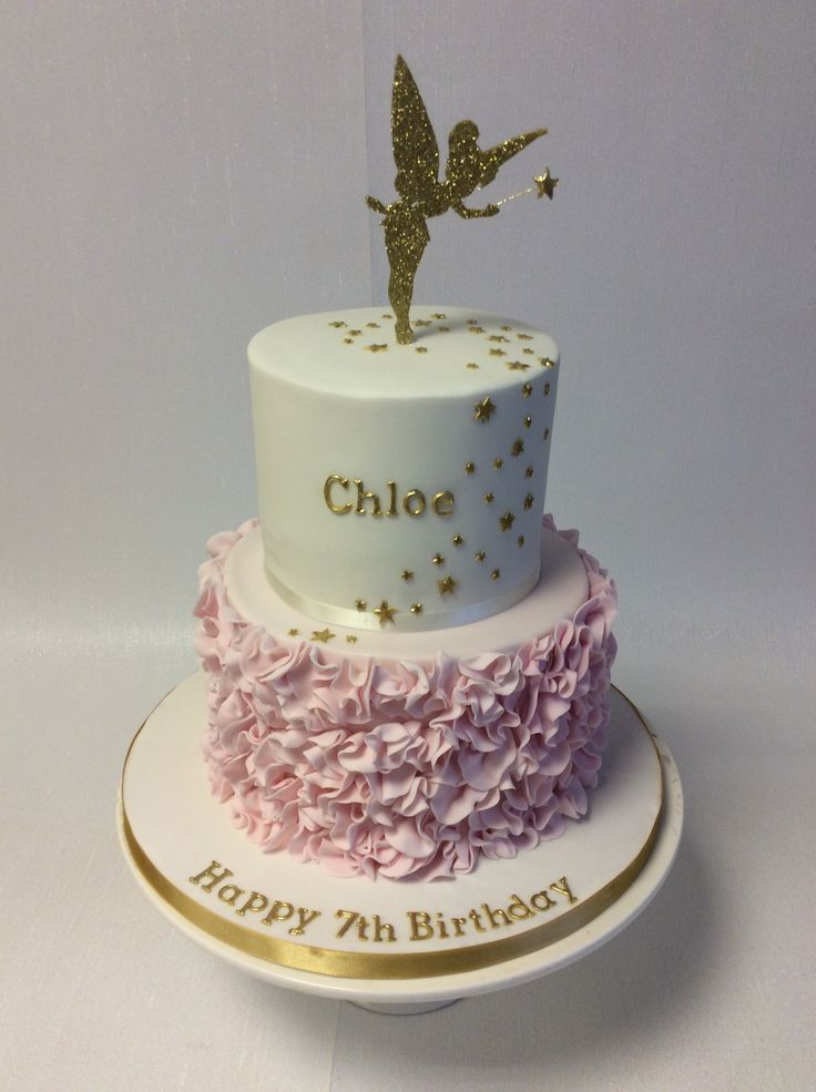 a white cake with pink flowers and a gold fairy on top