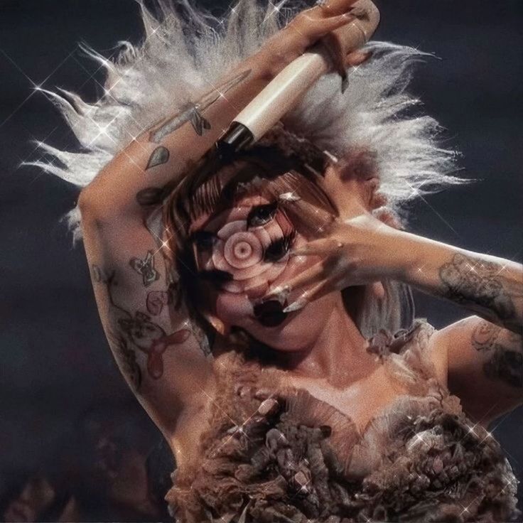 a woman with white hair and tattoos on her face is holding a microphone in front of her head