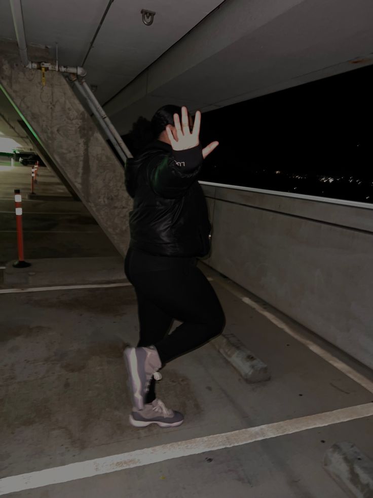 a woman in black jacket and leggings reaching up to grab something off the ground