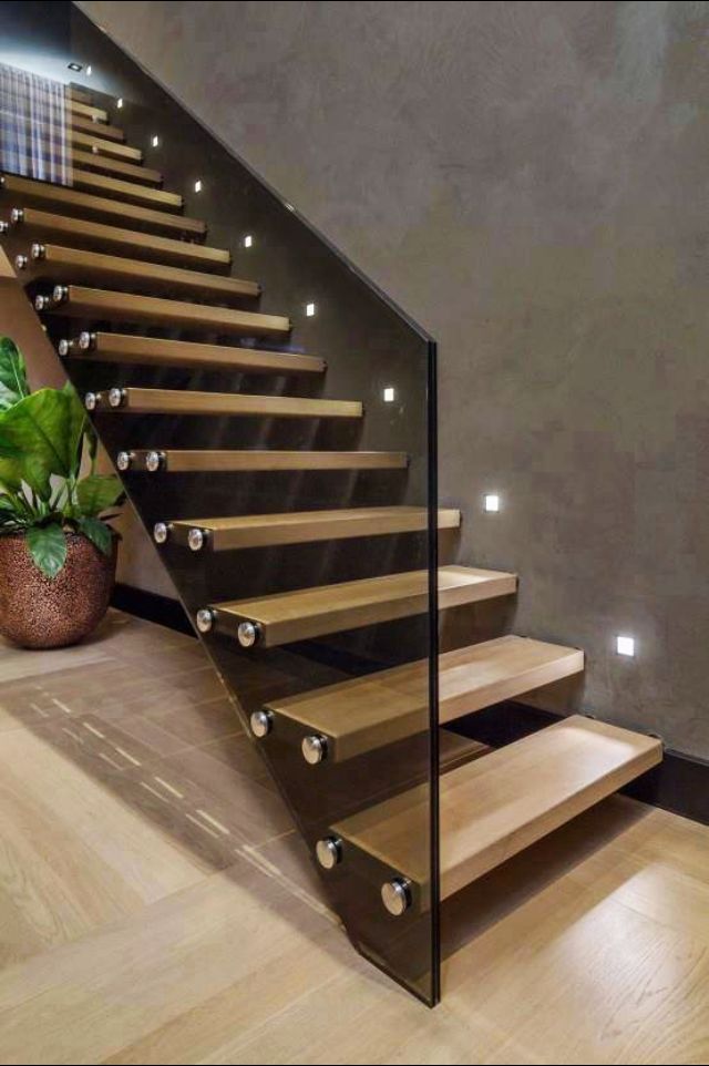 a wooden staircase with glass balustrades and metal handrails in a modern home