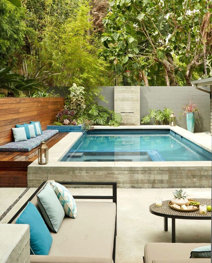 an outdoor living area with a pool and patio furniture in the foreground, surrounded by trees