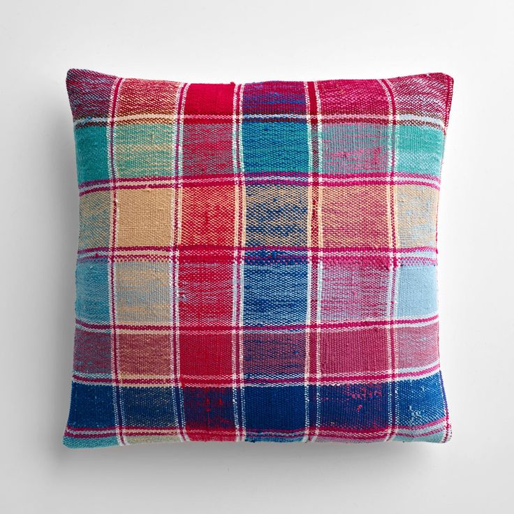 a colorful plaid pillow on a white wall