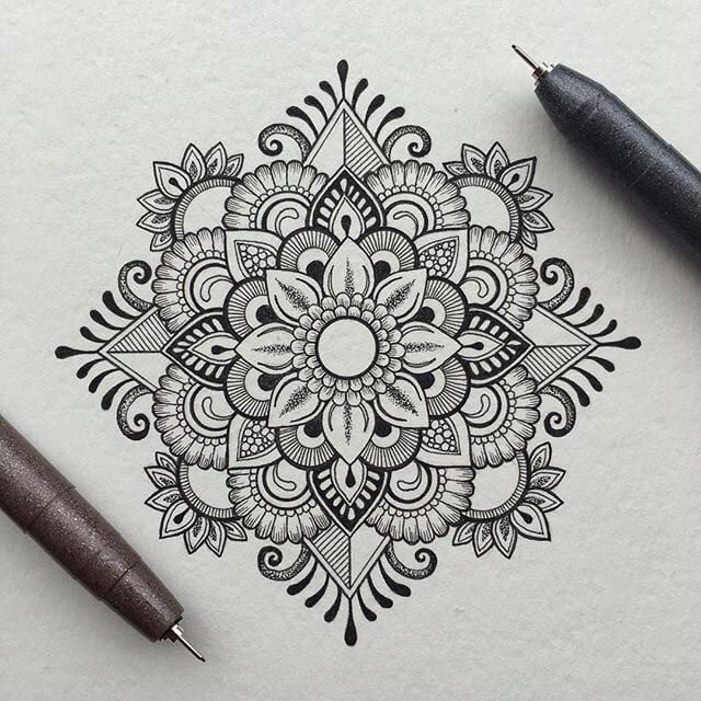 a pen and some ink sitting on top of a piece of paper with an intricate design