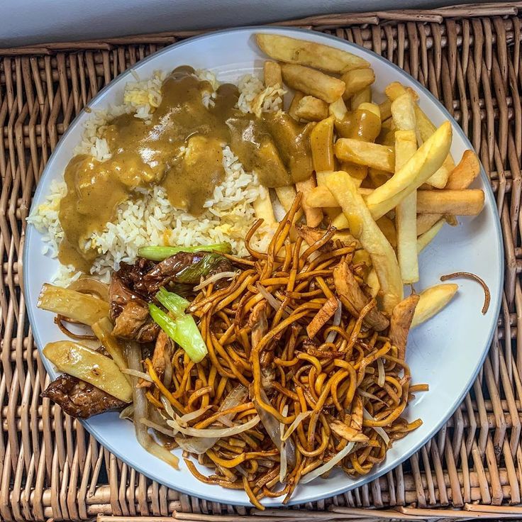 a white plate topped with lots of food next to french fries and gravy