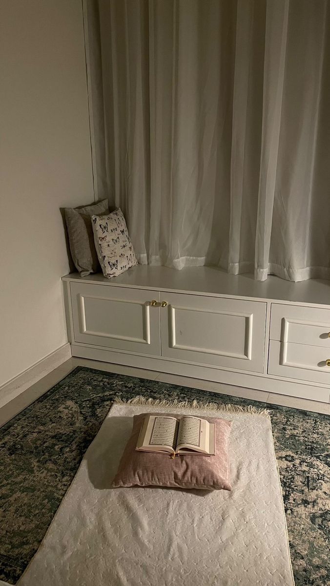 an open book sitting on top of a white rug next to a window sill