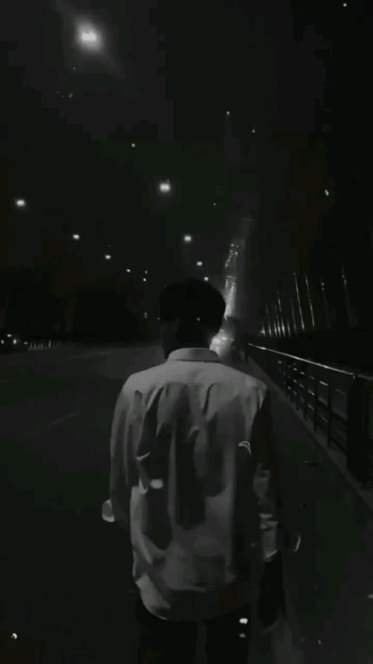 a man walking across a bridge at night