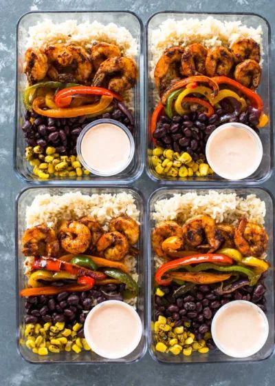 four trays filled with rice, beans and shrimp next to dipping sauce on the side