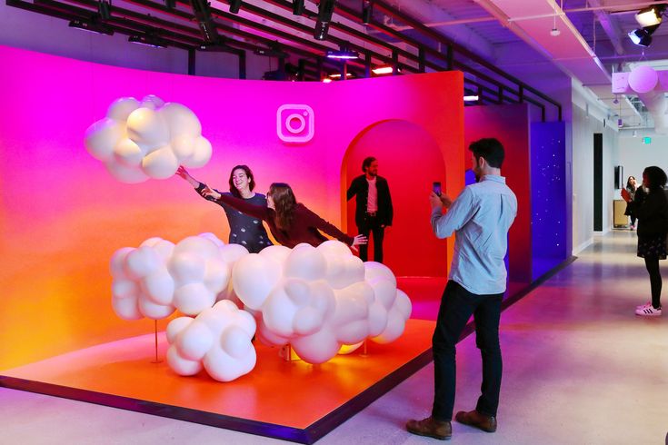 people are standing in front of an art display with balloons and clouds on it,