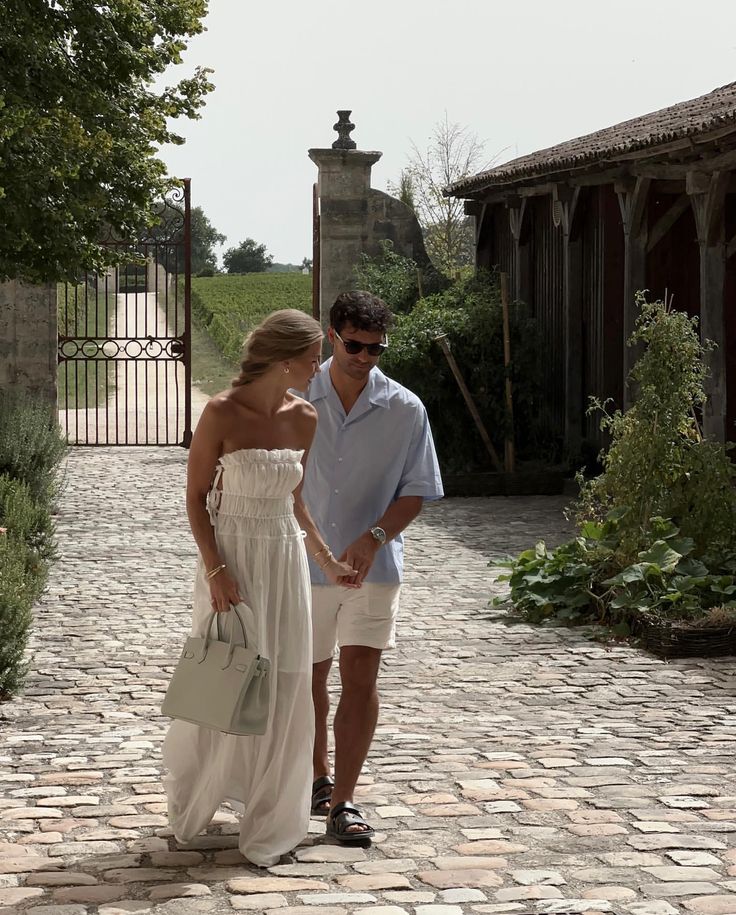 a man and woman walking down a cobblestone walkway