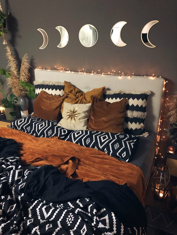 a bed topped with lots of pillows and blankets next to a wall mounted moon phases