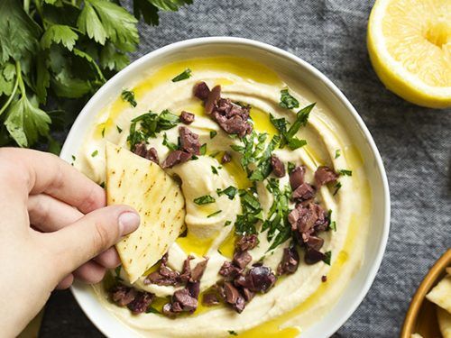 a bowl of hummus with pita chips and cilantro on the side