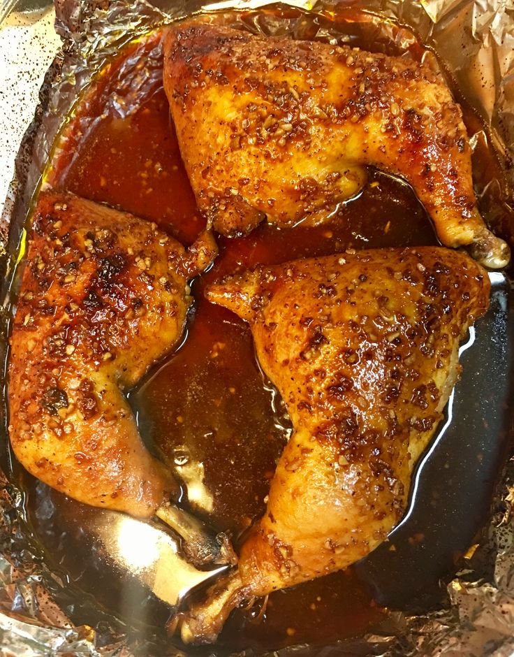 three pieces of chicken sitting on top of tin foil in a pan with brown sauce