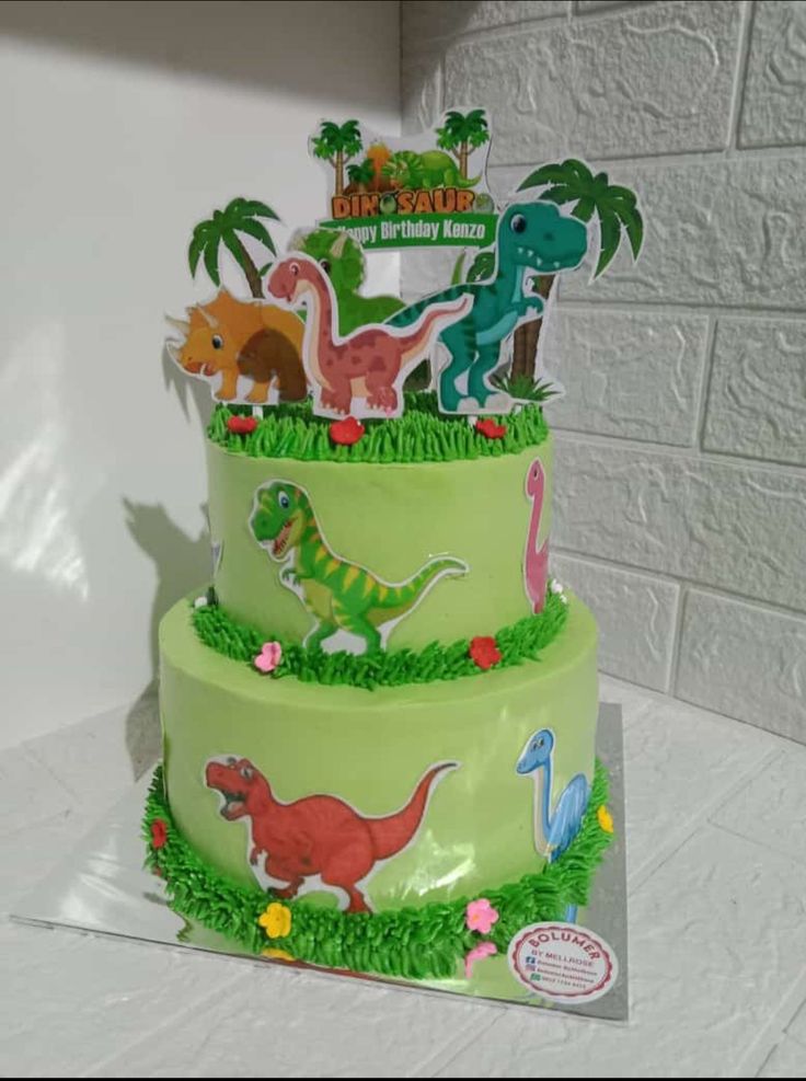 a three tiered cake decorated with dinosaurs