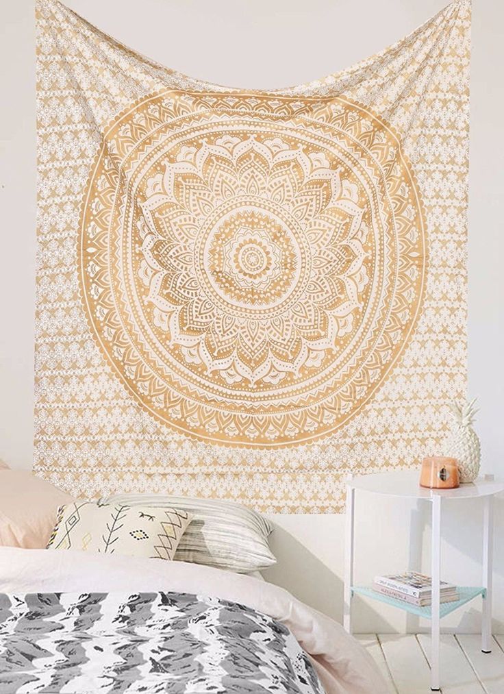 a large tapestry hanging on the wall above a bed in a room with white walls