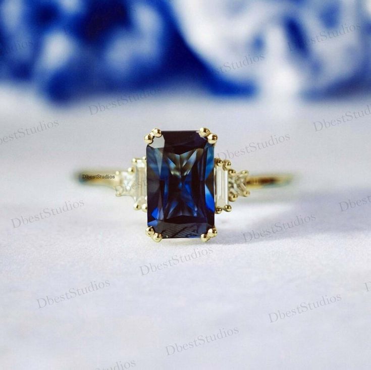 an engagement ring with a blue stone surrounded by three white diamonds on top of it