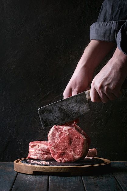 a person holding a knife over some raw meat