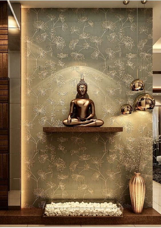 a buddha statue sitting on top of a wooden shelf in front of a wallpaper