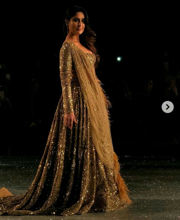 a woman is walking down the runway wearing a gold dress with sequins on it