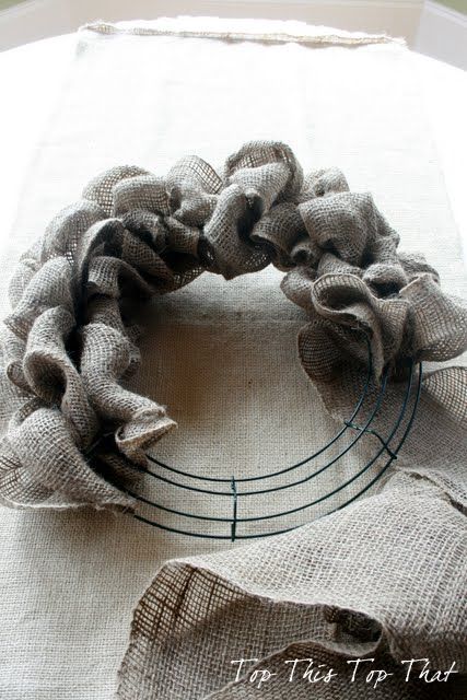 a close up of a wreath on a table with burlocks and flowers in the background