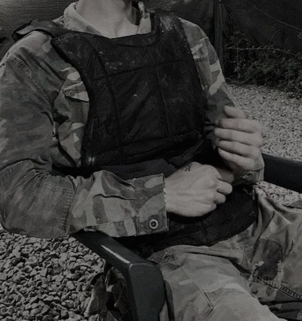 a man in camouflage sitting on a bench