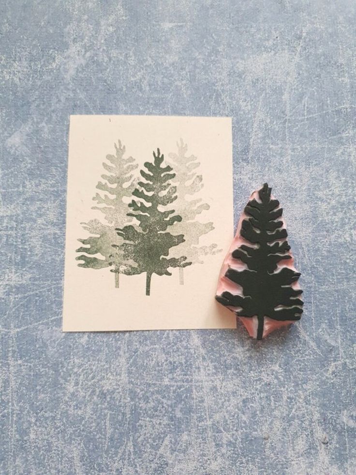 a stamp with a pine tree on it next to a piece of paper that has been cut out