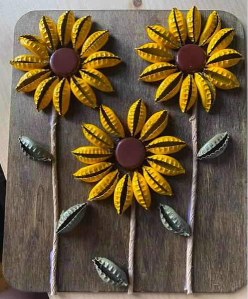 some yellow flowers are sitting on top of a wooden board with sticks and chocolate in the middle