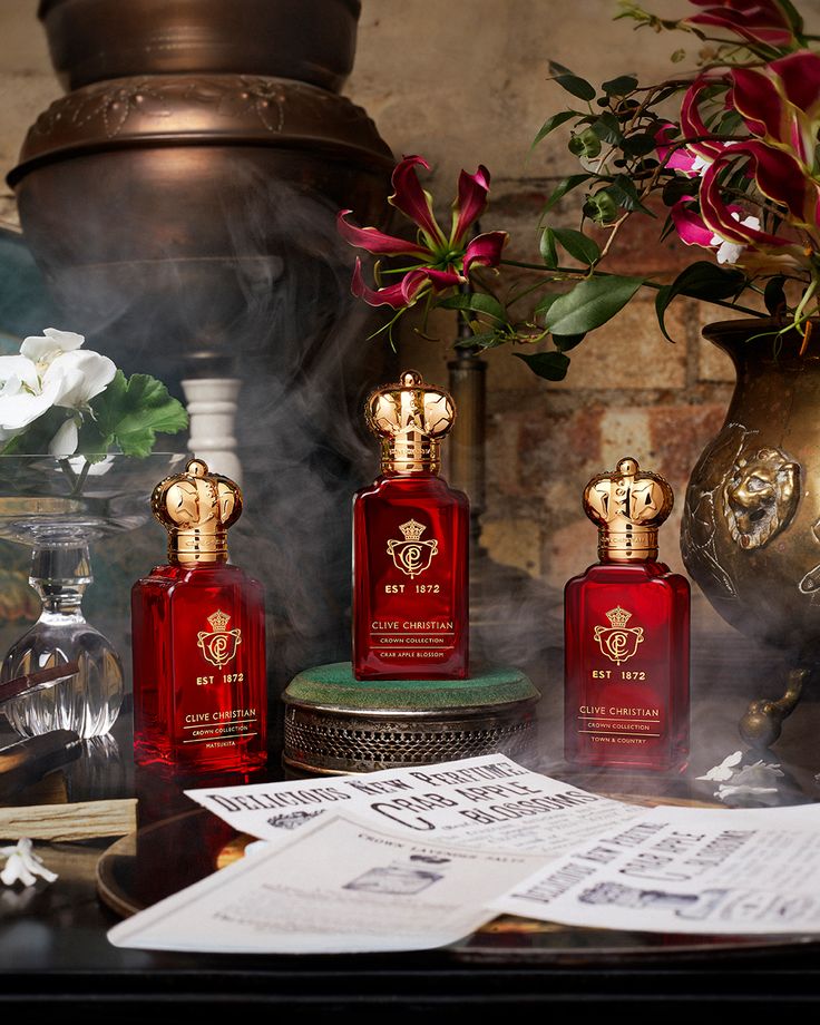 three red perfume bottles sitting on top of a table next to papers and vases