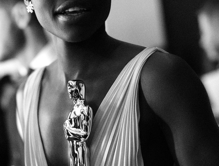 a black and white photo of a woman in a dress holding an oscar award trophy