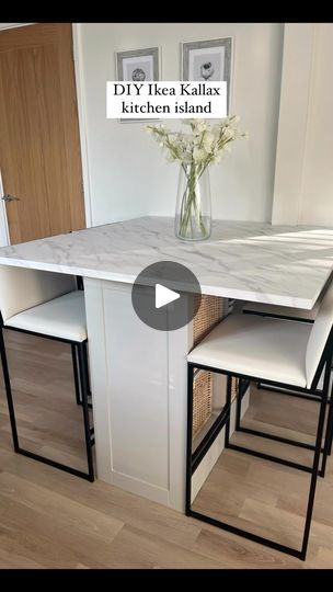 a kitchen island with two stools and a vase filled with flowers on top of it