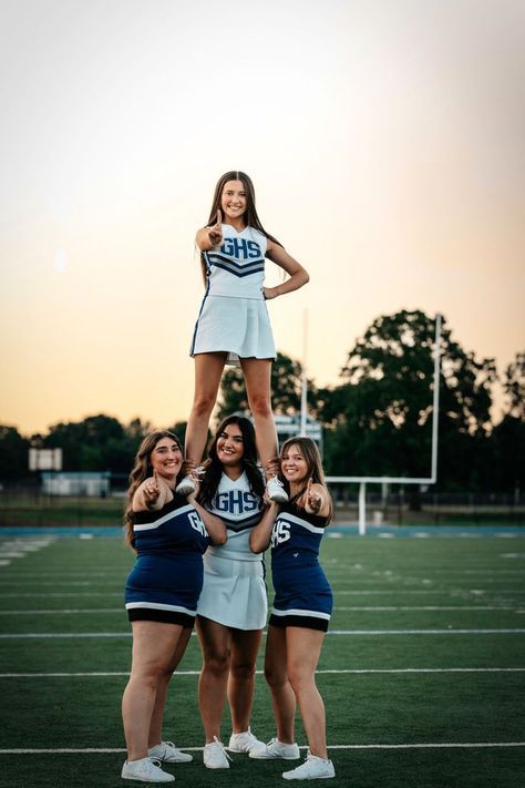 the cheerleaders are posing on top of each other in front of an empty football field