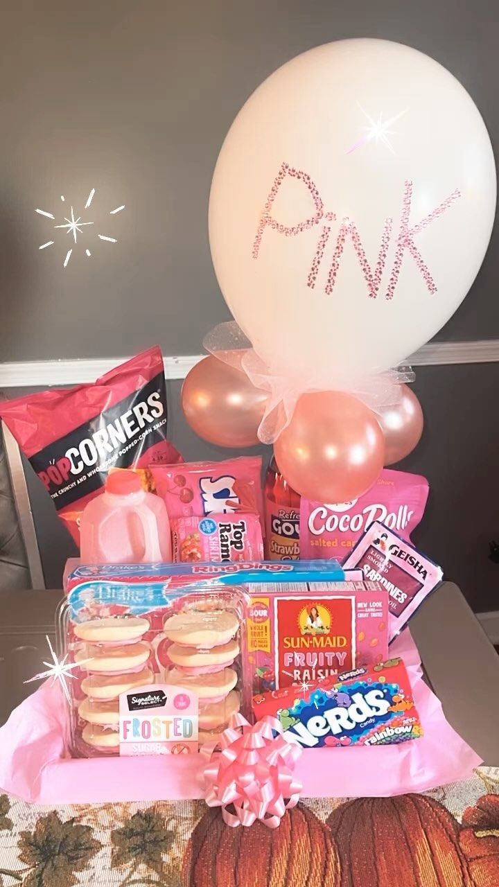 a table topped with balloons and snacks next to a balloon that says pink on it