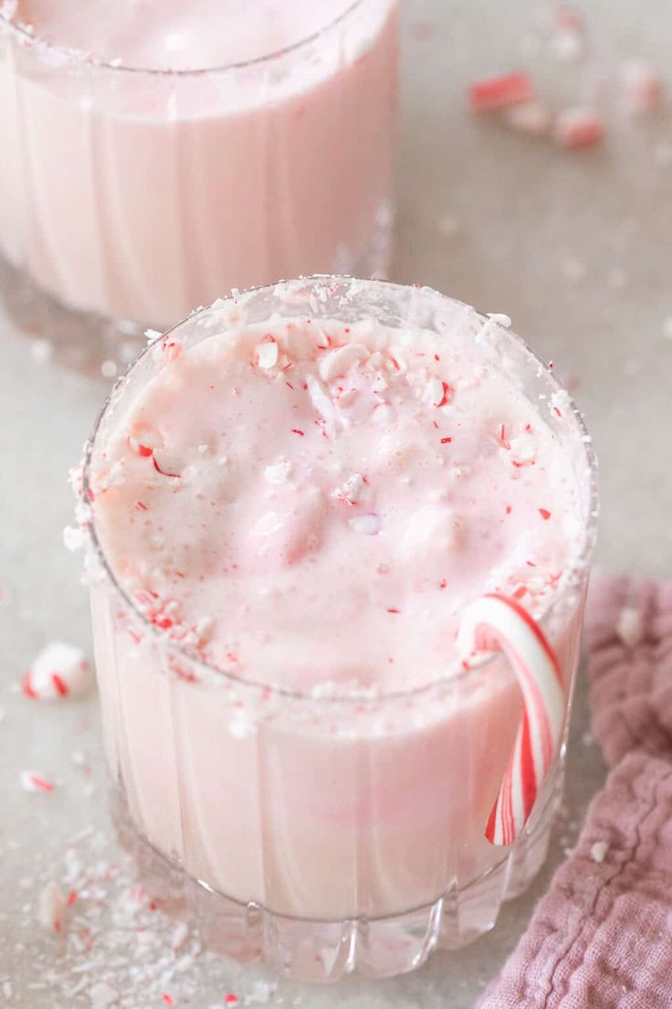 two glasses filled with candy cane milkshakes on top of a white countertop