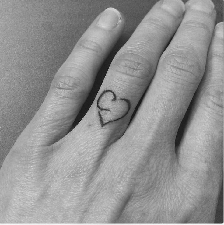 a woman's hand with a small heart tattoo on it