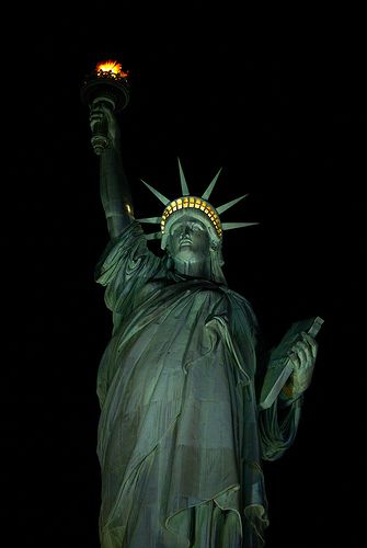 the statue of liberty is lit up at night with its torch in it's hand