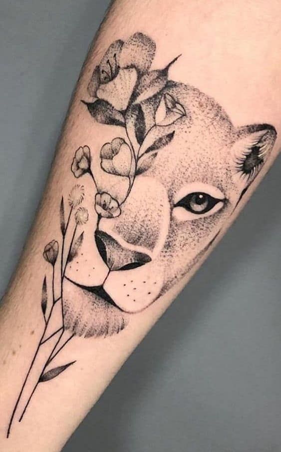 a black and white photo of a lion's face with flowers on its head