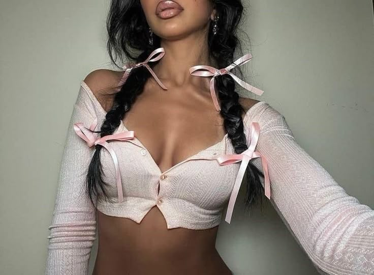 a woman with long black hair wearing a white bra and pink ribbon around her neck