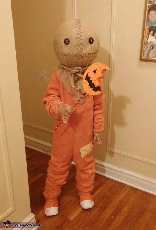 a little boy dressed up as a scarecrow holding a jack - o'- lantern