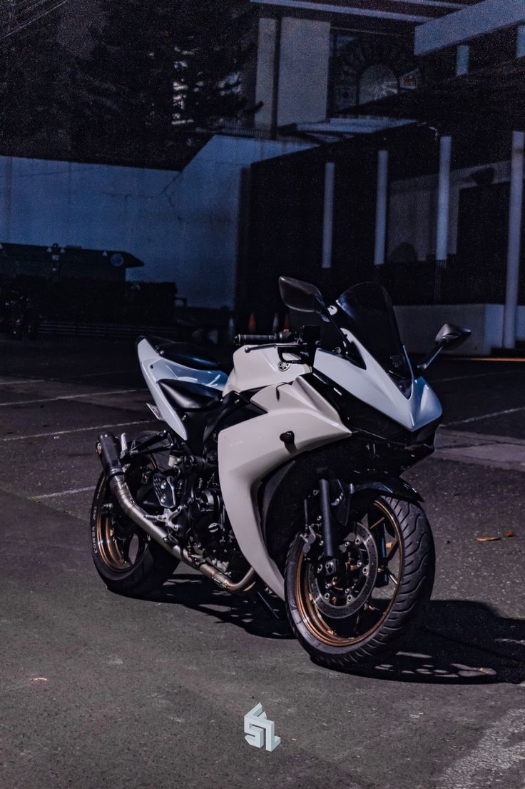 a white and black motorcycle parked in a parking lot next to a building at night