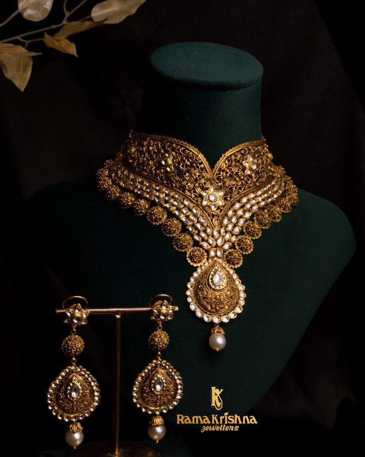 a gold necklace and earring set with pearls on display in front of a mannequin