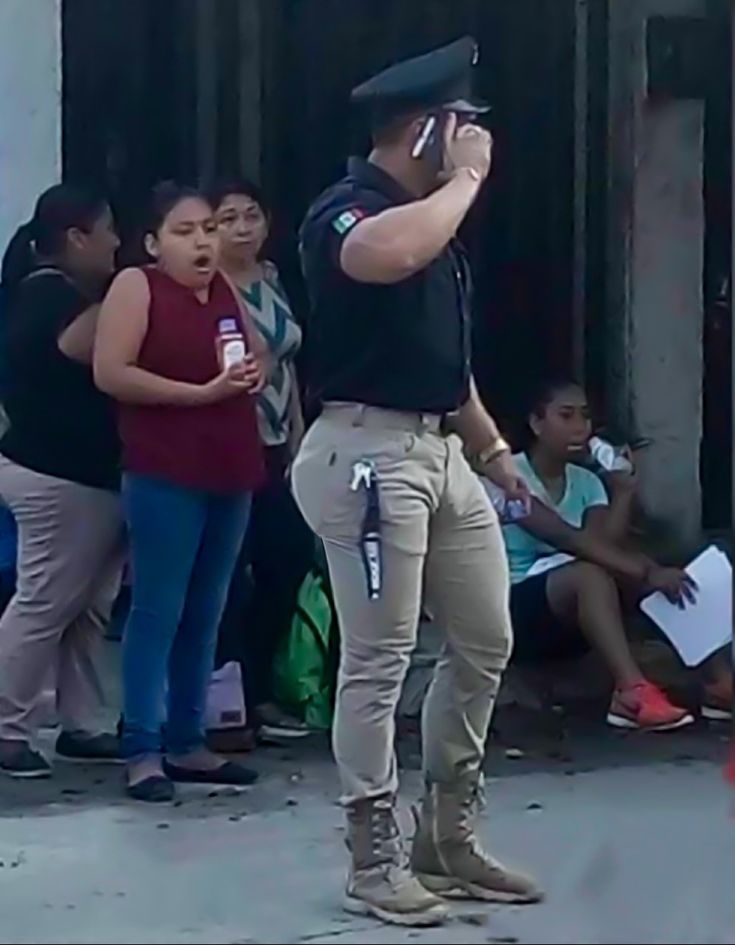 a man standing in front of a group of people on a cell phone and holding a camera up to his ear