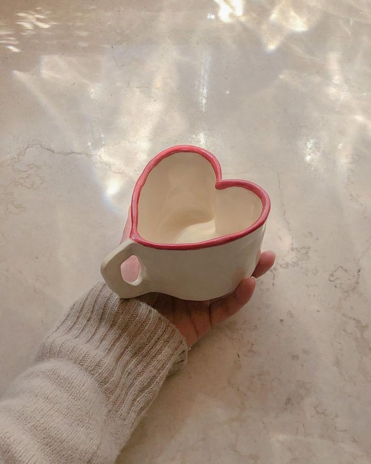 a hand holding a heart shaped coffee cup