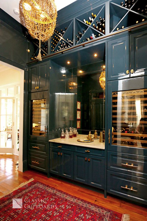 a kitchen with blue cabinets and a red rug on the wooden floor next to it