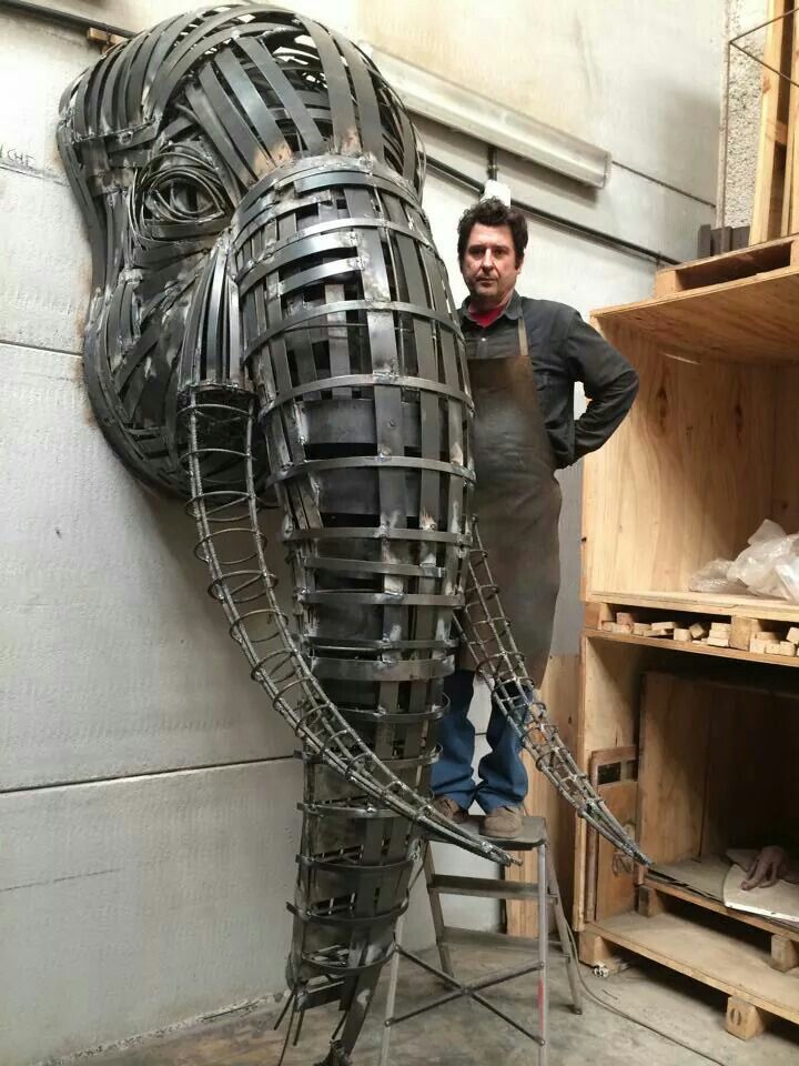 a man standing next to a giant metal horse head