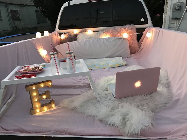 a laptop computer sitting on top of a white bed in the back of a truck