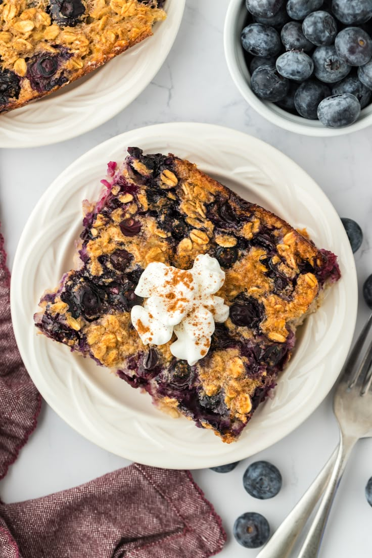 blueberry baked oatmeal bars on plates next to bowls of blueberries