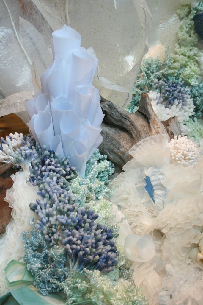 an arrangement of white and blue flowers on top of a piece of drifty wood